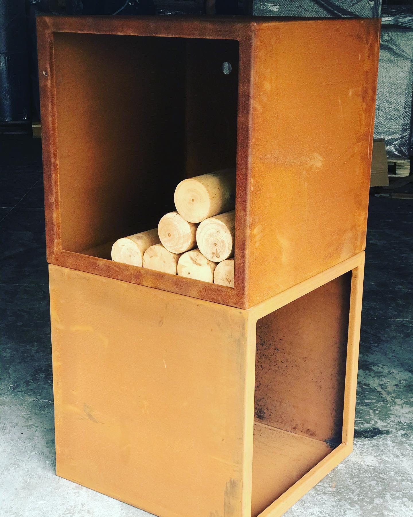 A brown corten steel wood storage unit with cubes and squares designed for firewood storage, placed indoors.